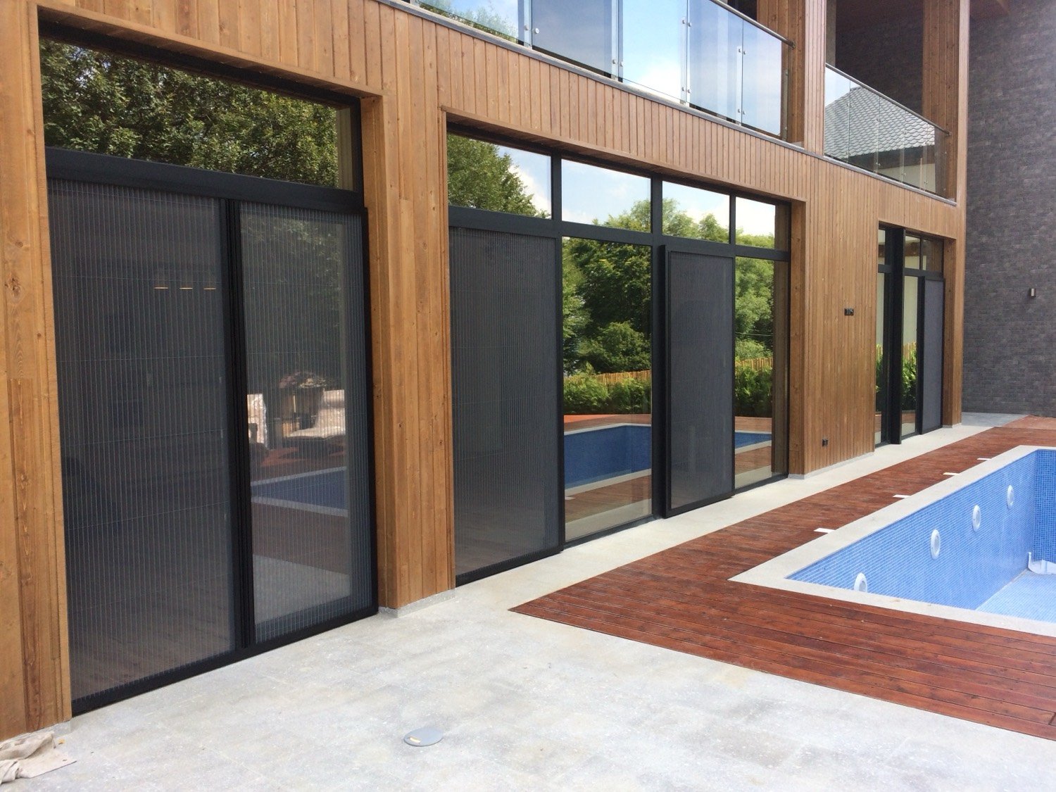 Black aluminum window and door system with safe glass railings and pleated screens for a private home in Kojori.